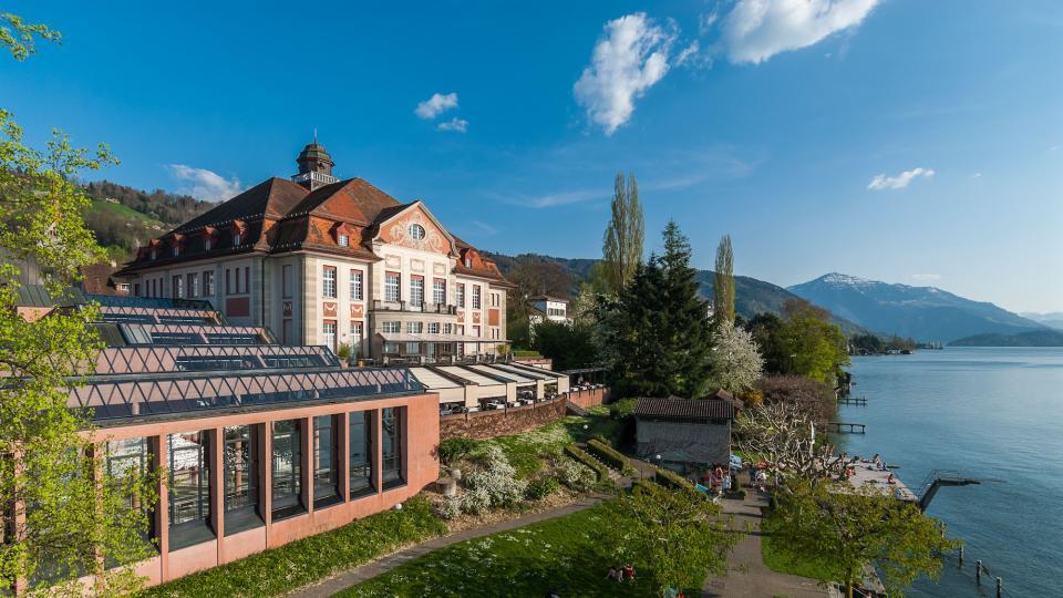 Frontansicht des neobarocken Theaters Zug mit dem See im Vordergrund und der Rigi im Hintergrund.