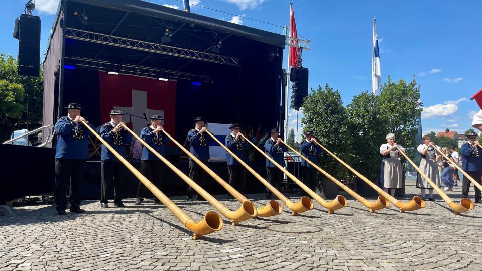 Ein Gruppe Alphronspieler tritt vor einer Bühne auf einem Kopfsteinpflaster Platz auf.