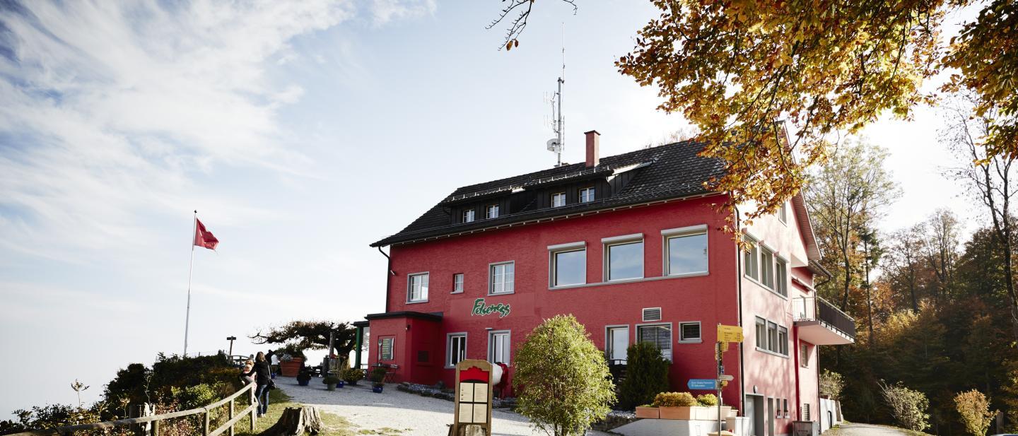 Das Restaurant mit der roten Fassade ist von herbstlichen Bäumen umgeben.